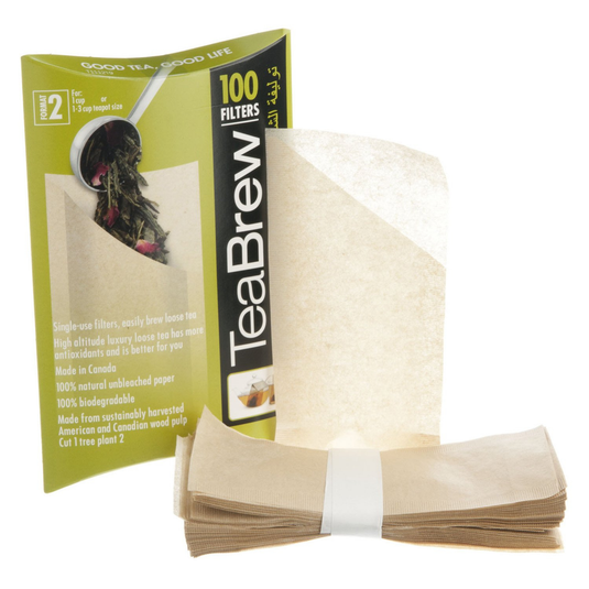 Translation missing: en.TeaBrew single-use filter bags shown with their green and black retail box on a white background. The box reads '100 Filters' and 'TeaBrew,' and a stack of beige filter papers tied with a white band is placed in front
